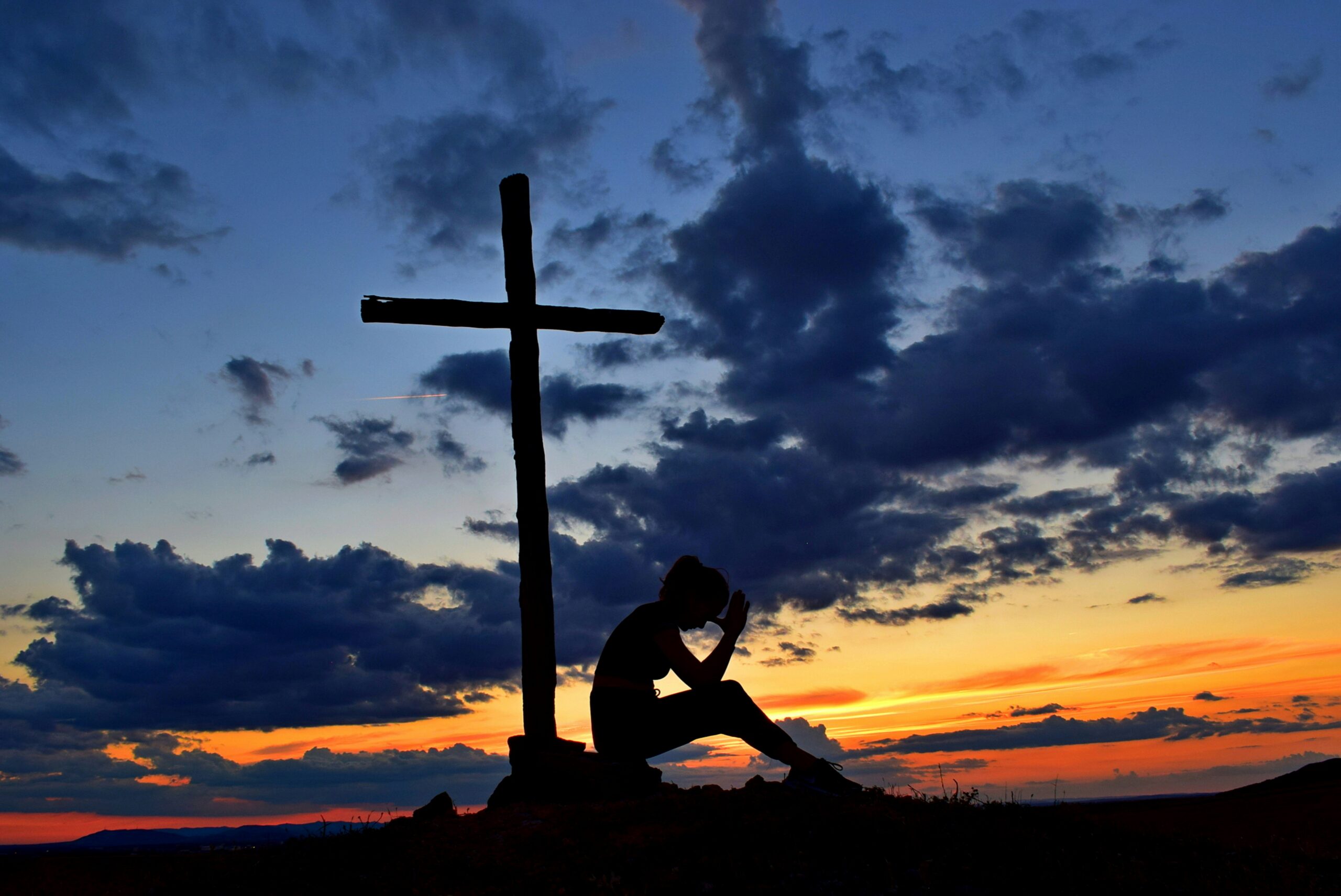 Woman praying by a cross